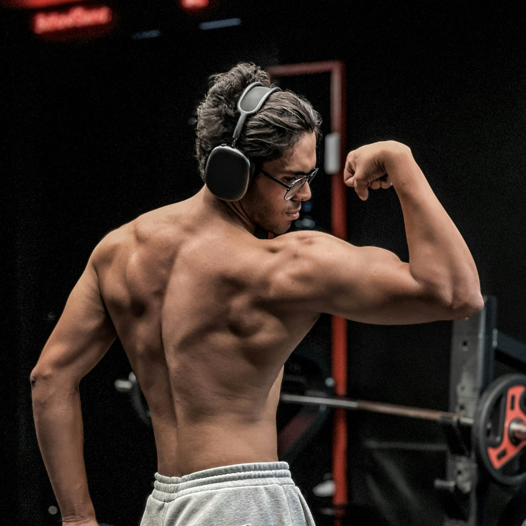Muscular man performing intense back exercises in a dark gym.