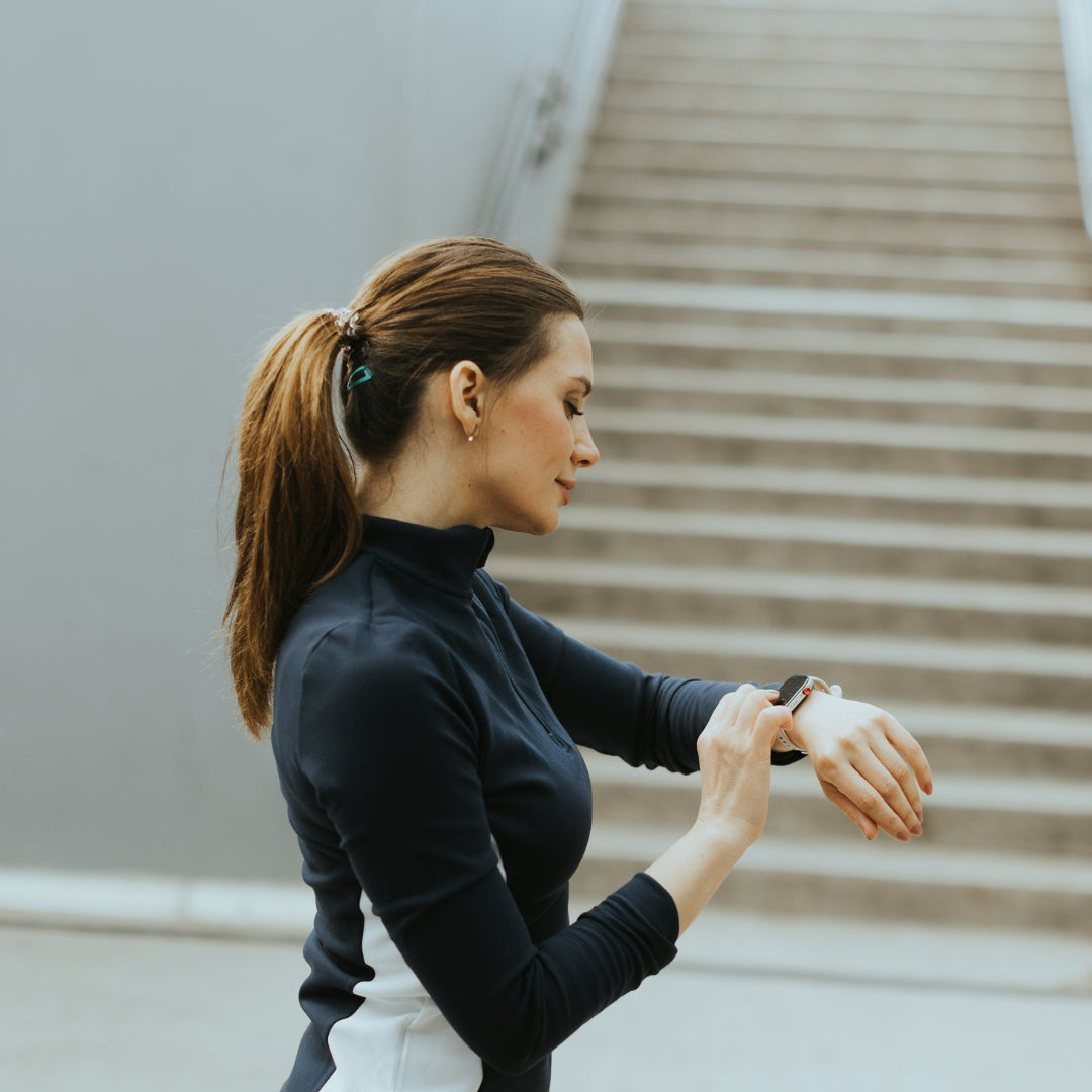 A woman in athletic wear checks her smartwatch after exercising.